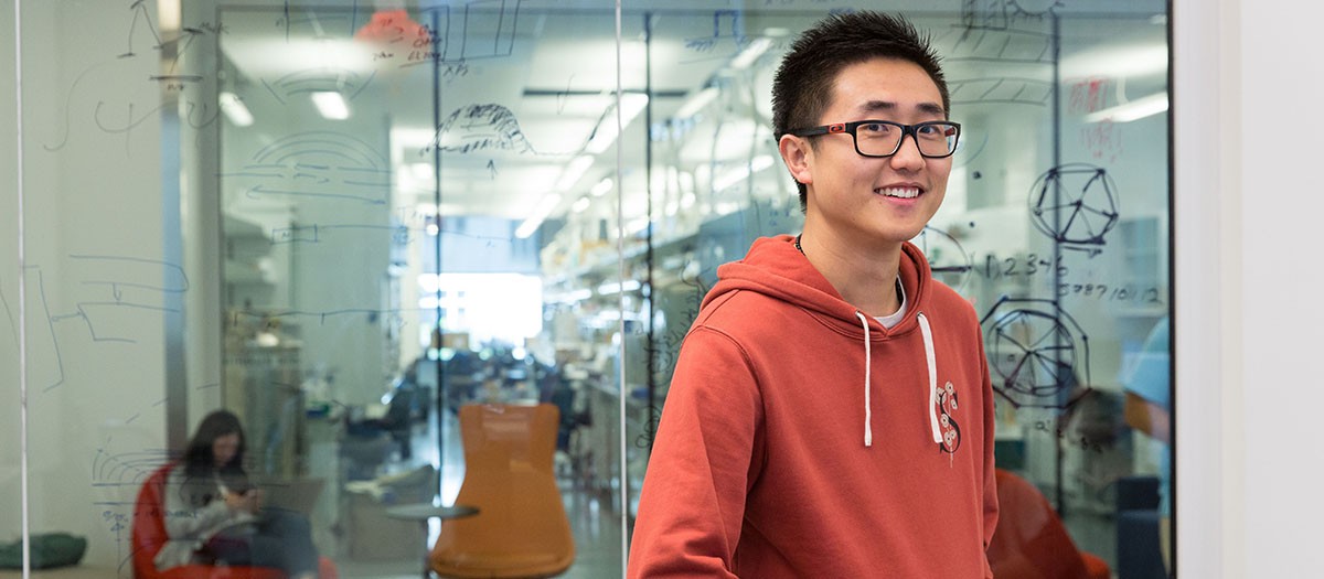 Student in front of glass with writing